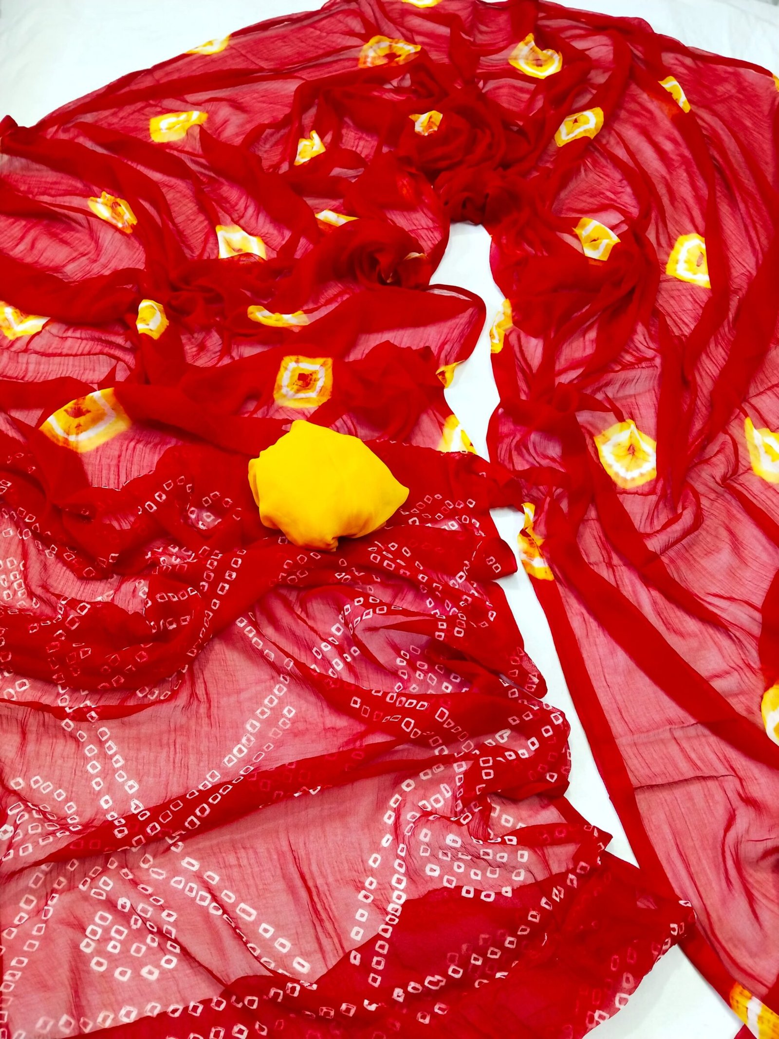 Nazneen Chiffon Bandhani Saree 7 A vibrant red Nazneen chiffon Bandhani saree displayed with a matching pink blouse piece.