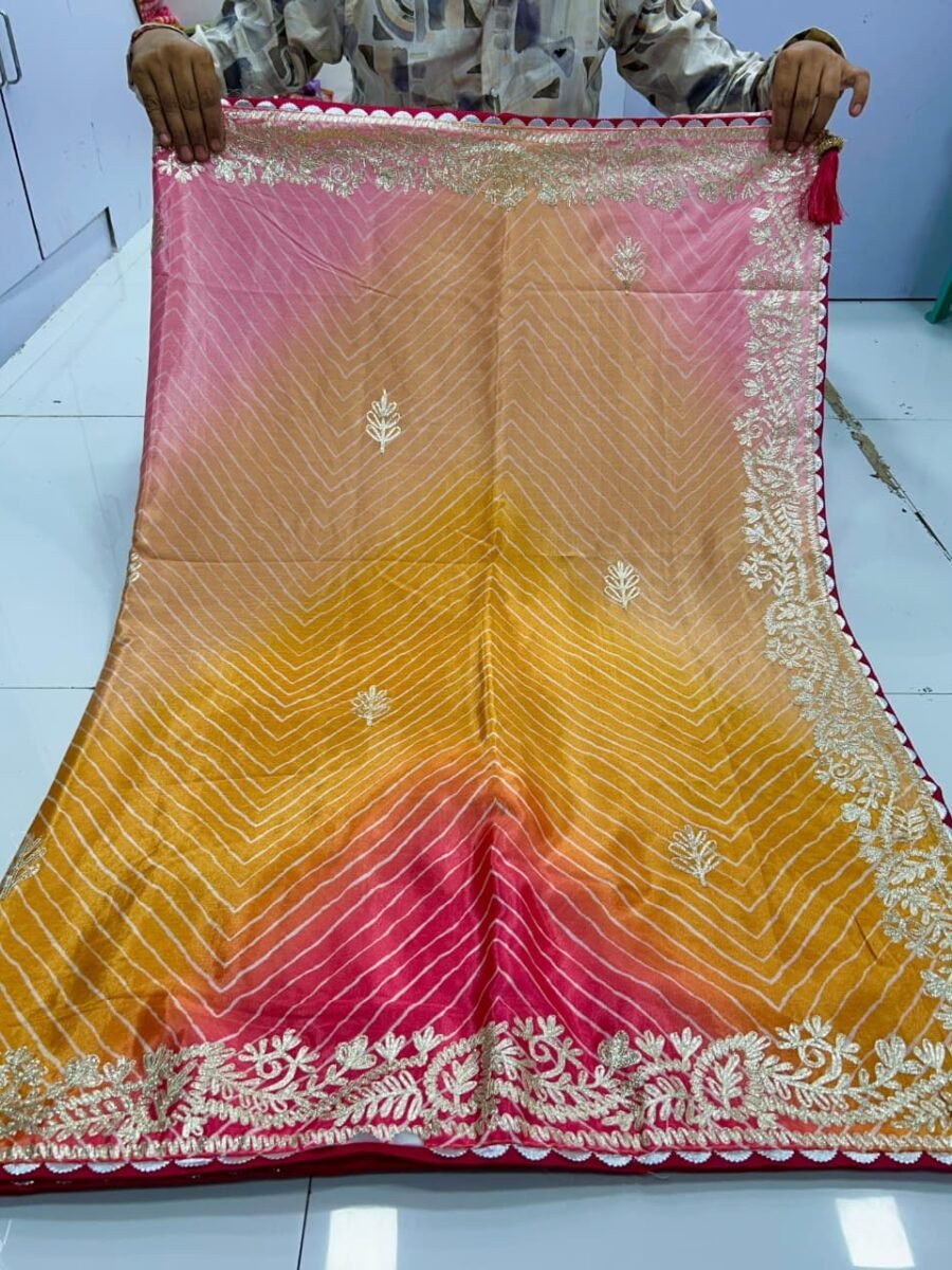 A beautiful pink and yellow gradient Leheriya saree in Chinnon fabric with intricate ribbon work border held by hands.