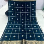 A beautiful red Chinon saree with heavy Zari work, butti, and a golden Jacquard border, being held up to display the design.