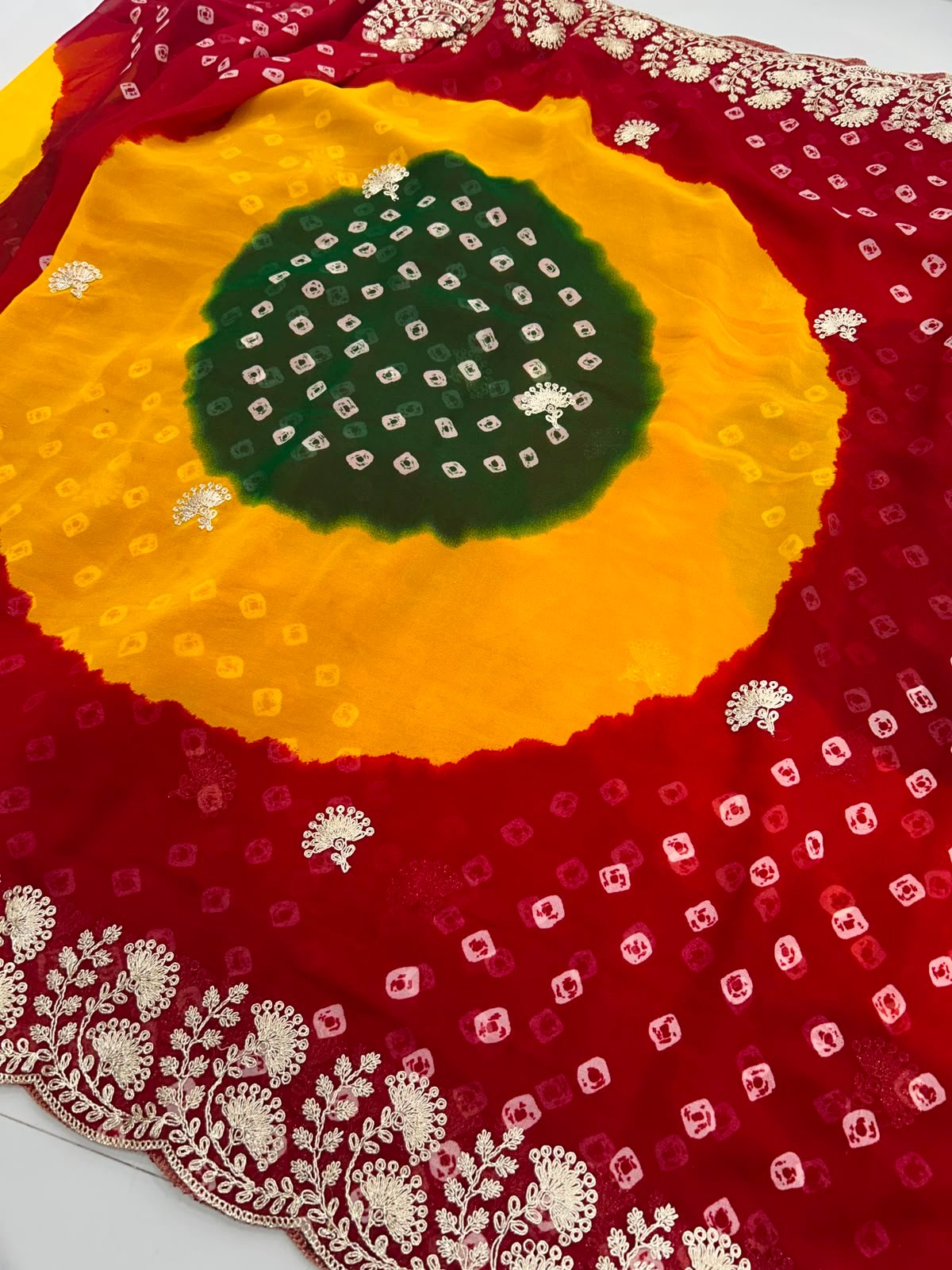 Chunri Bandhani Saree in Pure Georgette with Pita Work 3 A woman posing in the desert wearing a vibrant red, yellow, and green Chunri Bandhani saree with intricate pita work.