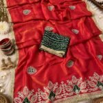 A beautiful red Cosmos silk saree featuring heavy Gota Patti work and Bandhej patches, displayed with matching bangles and earrings.