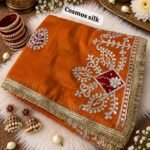 A beautiful red Cosmos silk saree featuring heavy Gota Patti work and Bandhej patches, displayed with matching bangles and earrings.