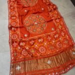 A beautiful red pure Modal Gajji Patola saree with intricate Gota Patti handwork and a metallic zari border spread across a tiled floor.
