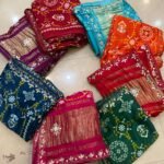A beautiful red pure Modal Gajji Patola saree with intricate Gota Patti handwork and a metallic zari border spread across a tiled floor.