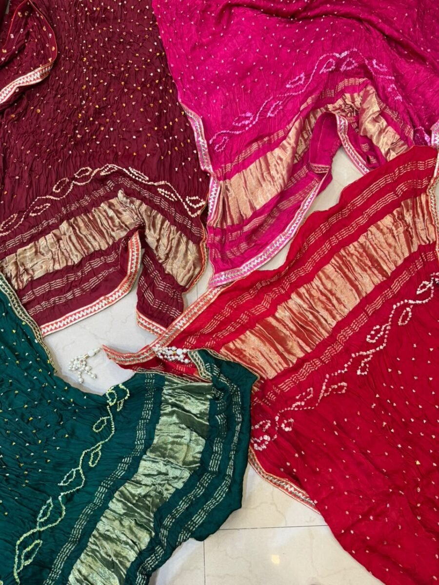 Three colorful Bandhej dupattas with Gota Patti borders and tassels displayed on a light surface.