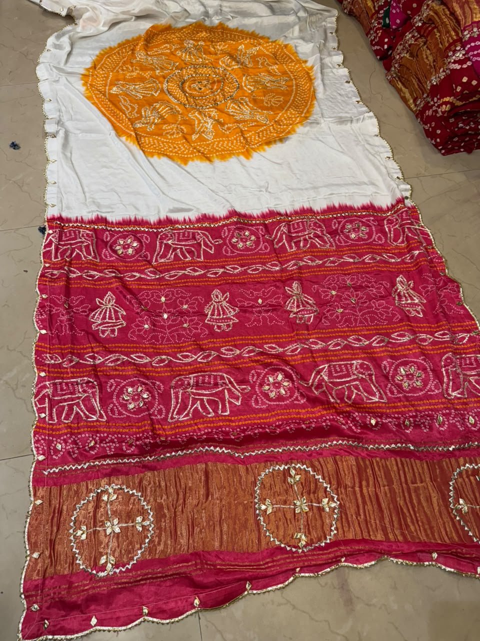 Pure Modal Gajji Silk Bandhej Saree with Gota Patti Work 2 A beautiful white and yellow Bandhej saree with a vibrant pink border featuring Gota Patti elephant and doll motifs.