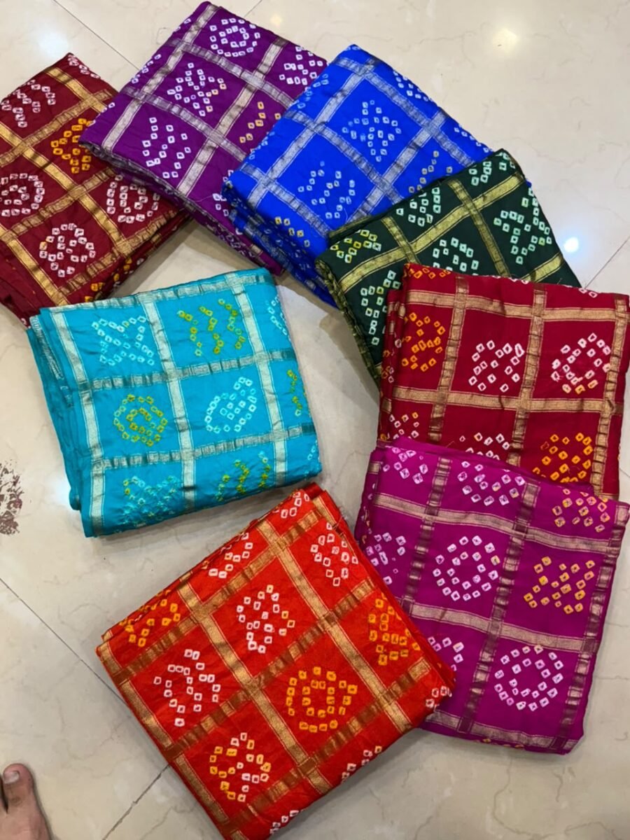 A collection of colorful gajji silk sarees with Bandhej patterns and zari checks laid out on a floor.