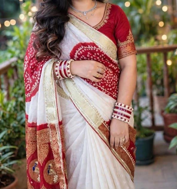A woman wears a stunning white and red Gajji silk Bandhej saree with heavy Zari borders and intricate Gota Patti work.