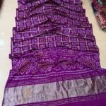 A collection of colorful gajji silk sarees with Bandhej patterns and zari checks laid out on a floor.