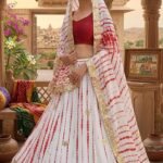 A woman wearing a white and red shibori printed lehenga with heavy Aari Gota Patti work and a matching dupatta.