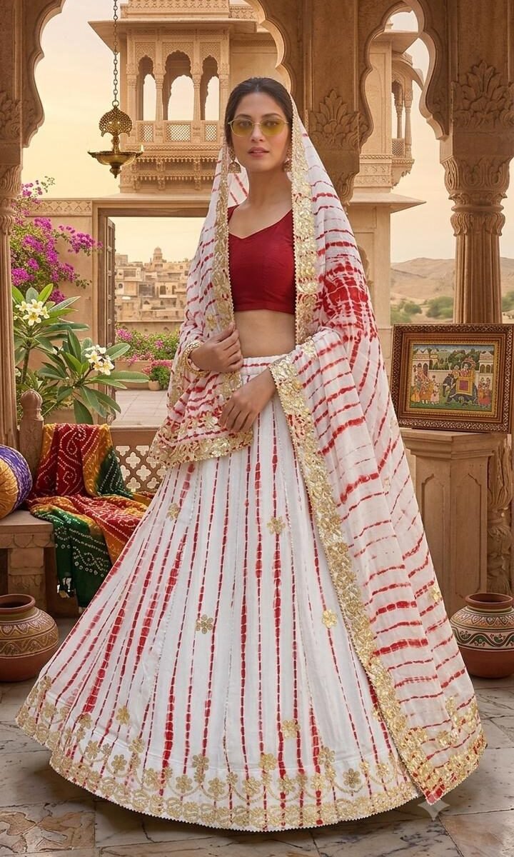 A woman wearing a white and red shibori printed lehenga with heavy Aari Gota Patti work and a matching dupatta.