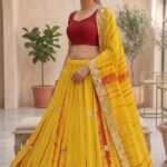A woman wearing a white and red shibori printed lehenga with heavy Aari Gota Patti work and a matching dupatta.