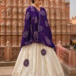 A woman wearing a vibrant orange and cream Gota Patti lehenga set stands in front of the Central Museum in Jaipur.