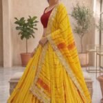 A woman wearing a white and red shibori printed lehenga with heavy Aari Gota Patti work and a matching dupatta.