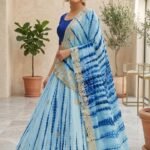 A woman wearing a white and red shibori printed lehenga with heavy Aari Gota Patti work and a matching dupatta.