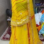 A woman wearing a white and red shibori printed lehenga with heavy Aari Gota Patti work and a matching dupatta.
