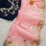 A beautiful deep purple Organza saree with detailed gold Gota patti handwork and a contrasting bright blue blouse piece.