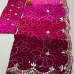 A vibrant Bandhani saree in shades of pink and maroon with intricate mirror work border and handwork motifs.