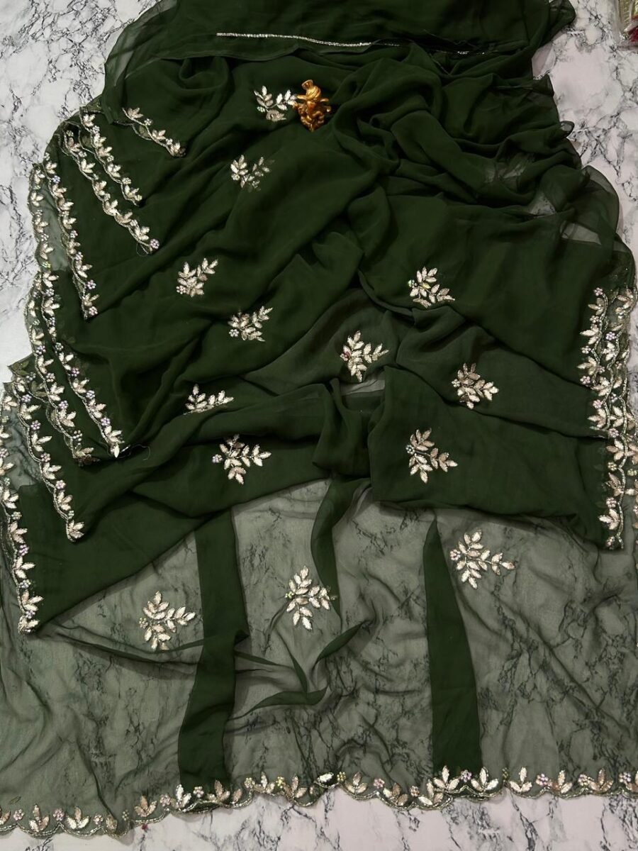 A deep green Royal Georgette saree with all-over handwork floral motifs and a detailed cutwork border laid on a marble surface.