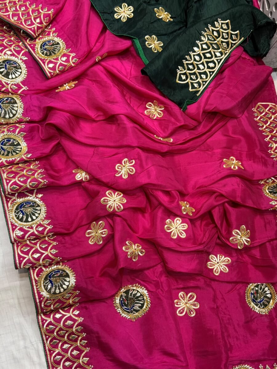 A stunning magenta Pure HO silk saree with heavy Kachhi Gota Patti and Moti work displayed with a matching dark green blouse.