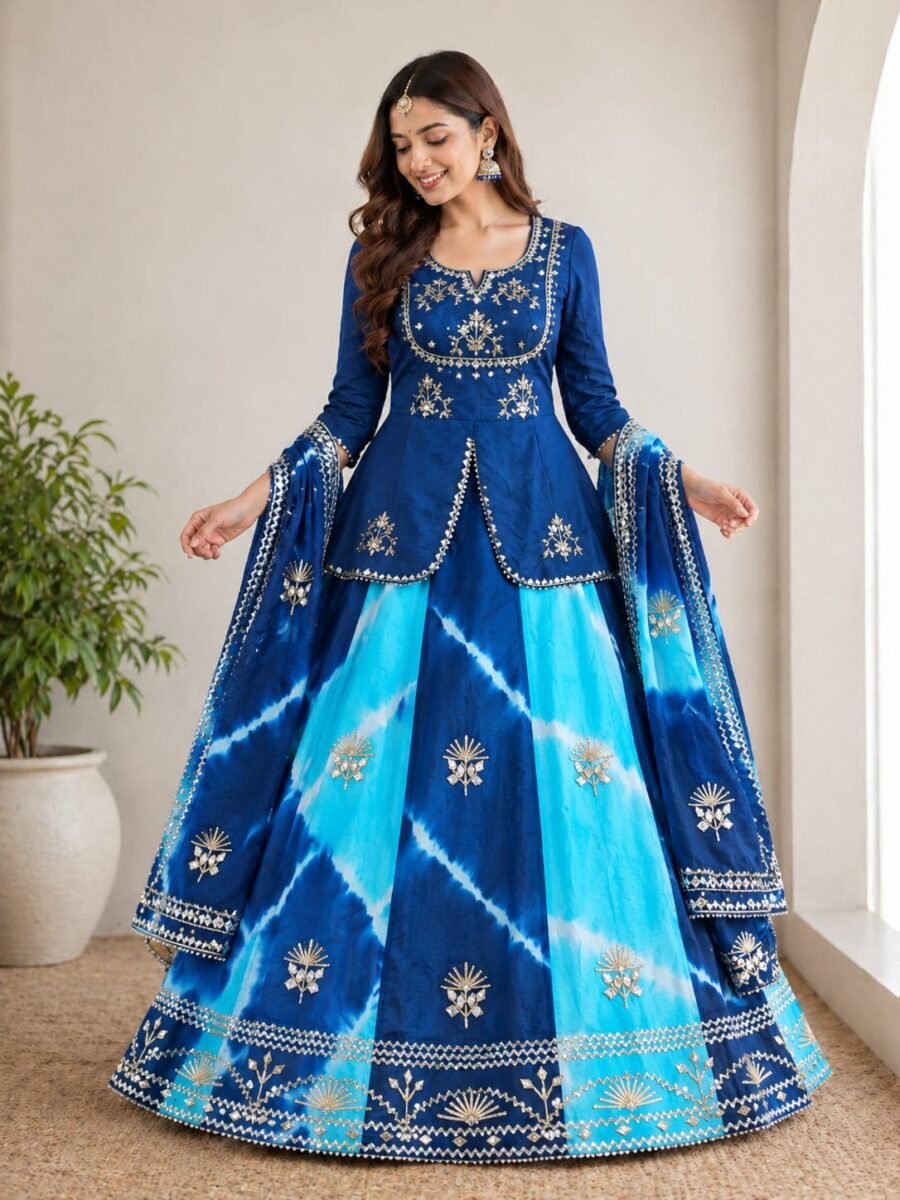 A woman posing in a blue and sky blue tie-dye pattern Chinon silk lehenga set with intricate Gota Patti handwork on a peplum blouse.