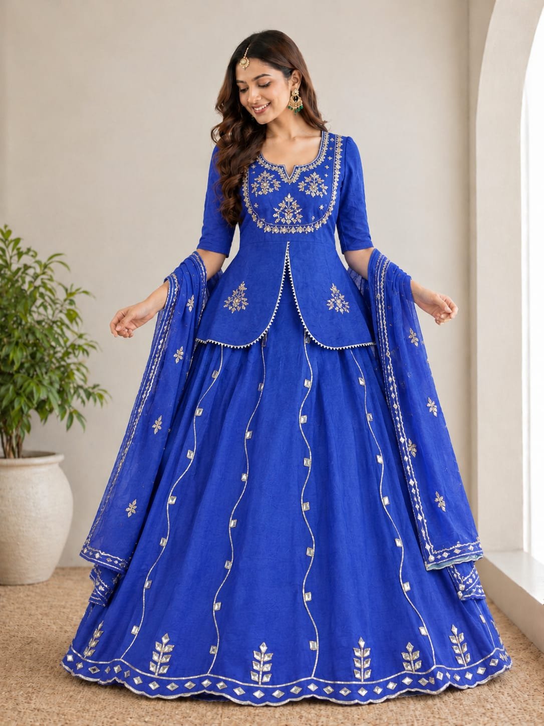 Jaipuri Lehenga with Gota Patti Work in Chinon Silk 6 A woman posing in a blue and sky blue tie-dye pattern Chinon silk lehenga set with intricate Gota Patti handwork on a peplum blouse.