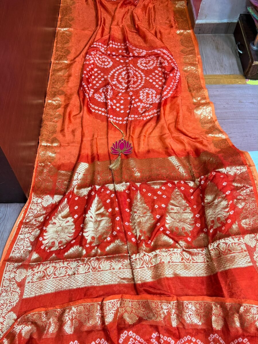 A vibrant orange Pure Jamnagari Silk Bandhej saree with intricate golden zari border and a hand-woven zari pallu.