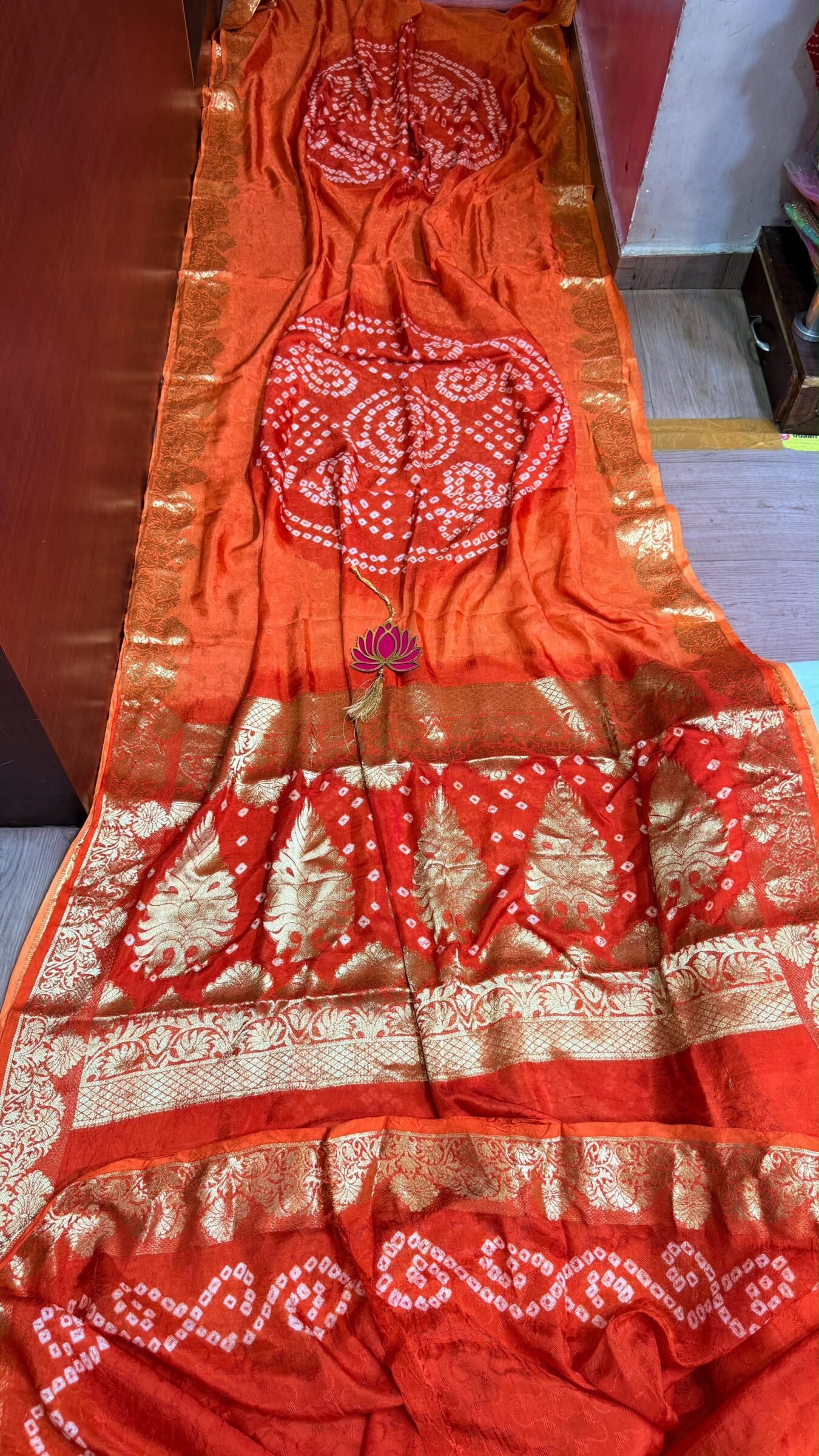 Pure Jamnagari Silk Bandhej Saree with Zari Border 1 A vibrant orange Pure Jamnagari Silk Bandhej saree with intricate golden zari border and a hand-woven zari pallu.
