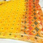 A close-up of a pink and orange Pure Khadi Jhorjhat Banarashi Bandhej saree with heavy zari and meena work.