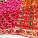 A close-up of a pink and orange Pure Khadi Jhorjhat Banarashi Bandhej saree with heavy zari and meena work.