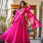 A woman wearing a vibrant pink Leheriya printed lehenga set with heavy embroidery and a matching bandhej dupatta.