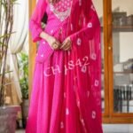 A woman wearing a vibrant pink Leheriya printed lehenga set with heavy embroidery and a matching bandhej dupatta.