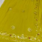 A bright yellow pure 30g Georgette saree with aari machine work and mirror embellishments along the border and fabric.