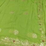 A bright yellow pure 30g Georgette saree with aari machine work and mirror embellishments along the border and fabric.