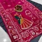 A wine coloured Dola silk saree featuring mirror work, zari butti, and an embroidered border laid out flat.
