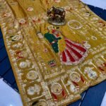 A wine coloured Dola silk saree featuring mirror work, zari butti, and an embroidered border laid out flat.