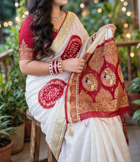 A woman wearing a white and red Pure Modal Gajji Silk Bandhej Saree with heavy zari and gota patti border.