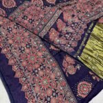 A close-up of a beautifully folded Modal Gajji Silk saree featuring rich golden and red hues with traditional mirror work and intricate hand-print patterns.