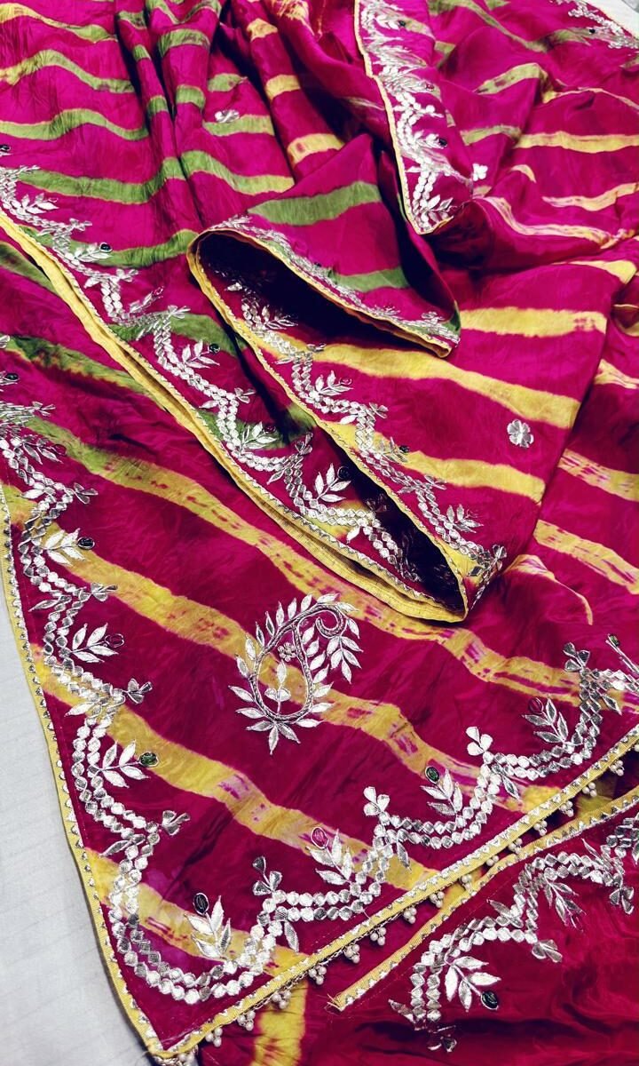 A beautiful pink and yellow Leheriya saree made of pure Moonga silk with intricate silver Gota Patti embroidery along the border.