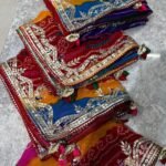 A stack of vibrant multi-colored Navranga Georgette sarees with intricate Gota Patti border work and tassels.