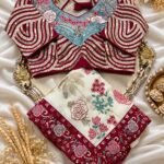 A beautiful white and maroon Rangoli Silk saree displayed with a heavy embroidered stitched blouse on a silver tray.