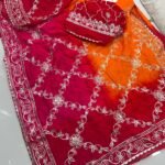 A woman wearing a vibrant orange and pink Russian crepe silk saree with elegant gota lace border and sequence embroidery.