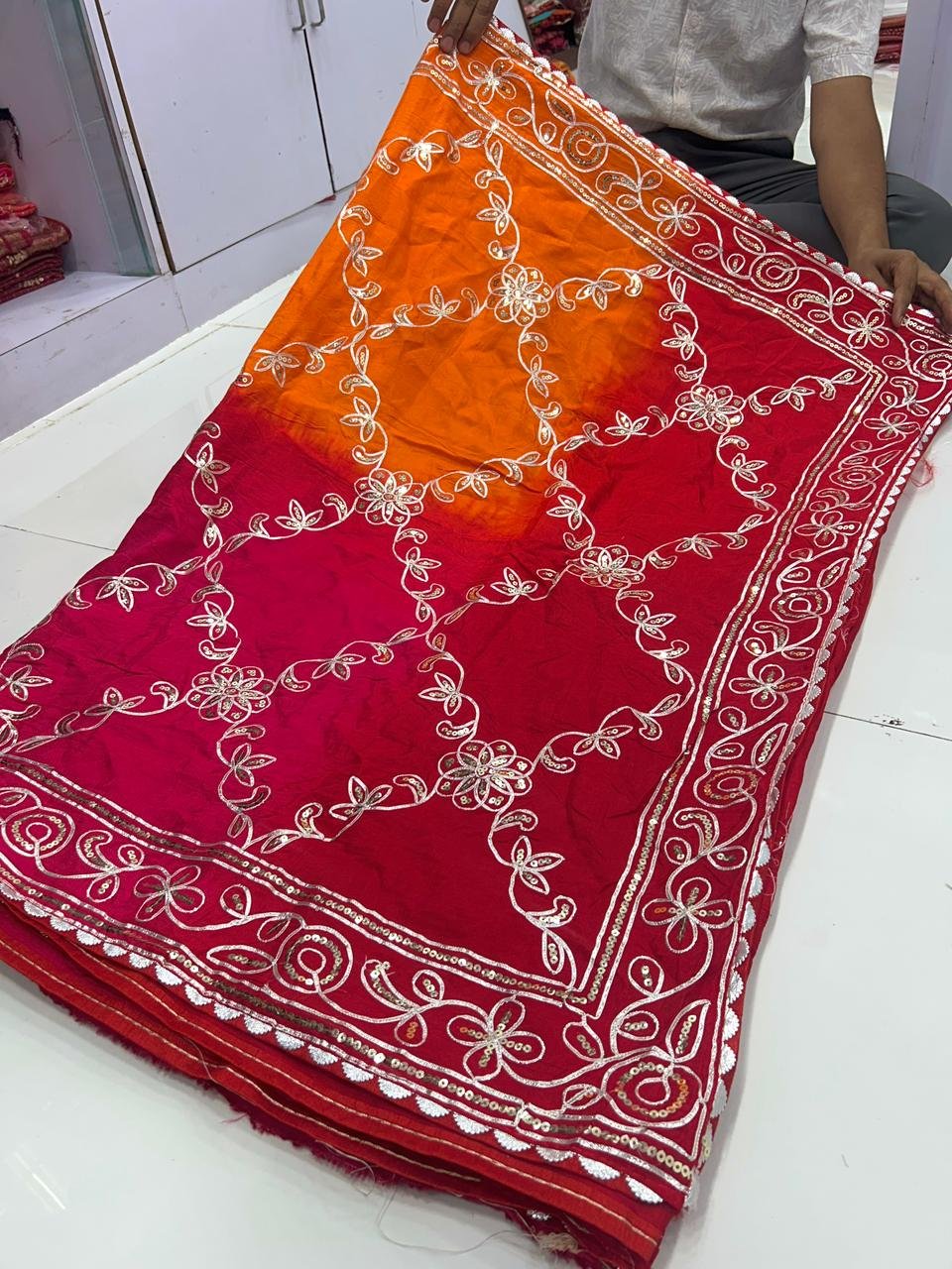 Russian Crepe Silk Saree with Gota Patti and Sequence Work 3 A woman wearing a vibrant orange and pink Russian crepe silk saree with elegant gota lace border and sequence embroidery.