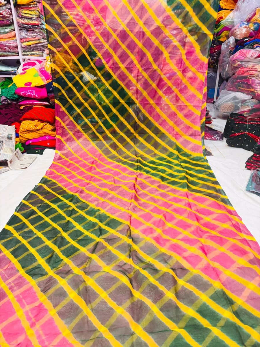 A vibrant Tora Silk Leheriya saree featuring diagonal yellow, pink, and dark green stripes laid out on a white surface.